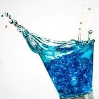 Vaso de agua fluoración derramando y salpicando gotas de agua