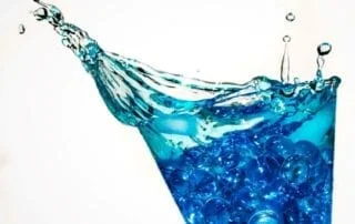 Glas water met morsen van fluoride en opspattende waterdruppeltjes